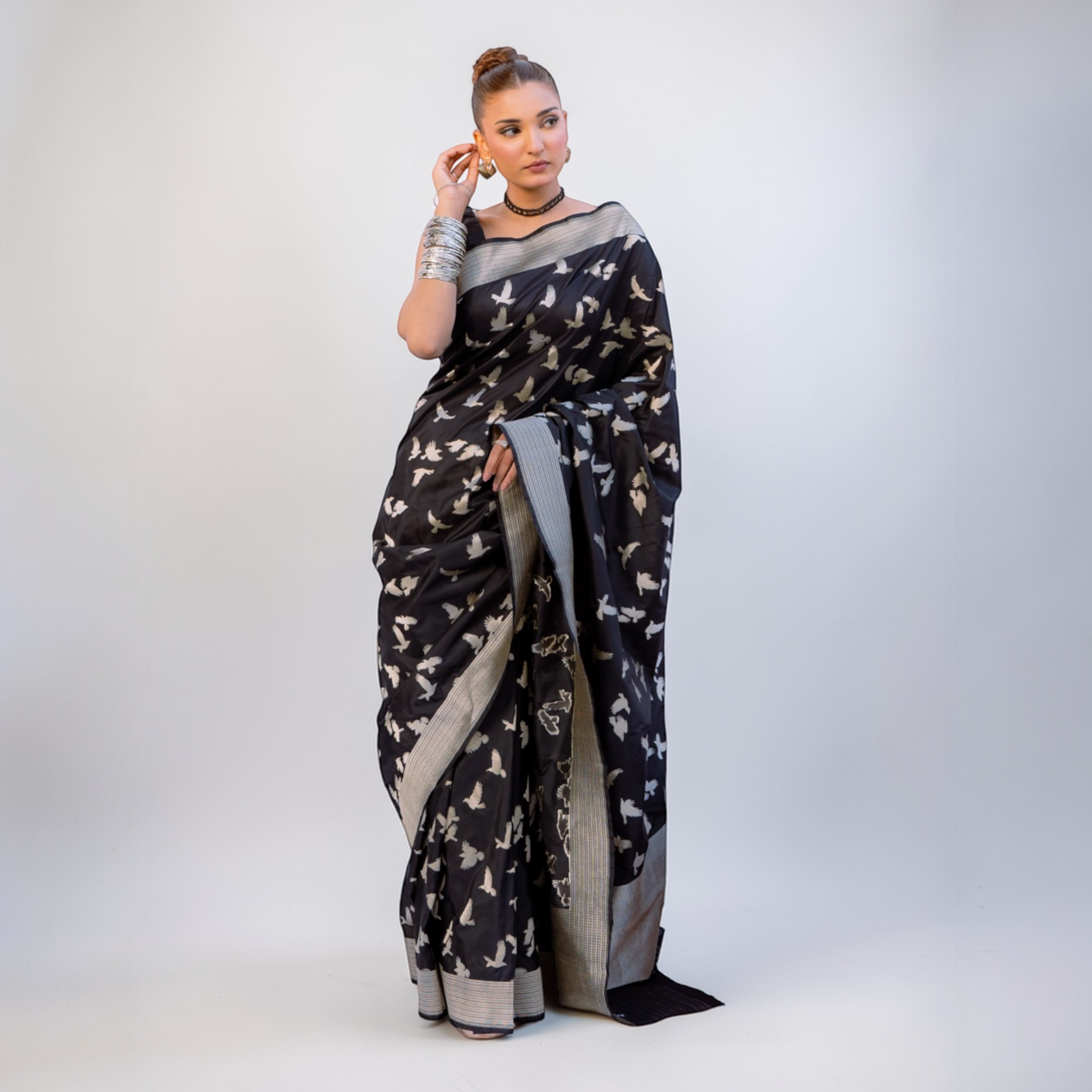 Woman wearing a black banarasi saree with white patterns on a white background Lunarae London